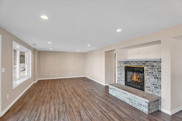 unfurnished living room with recessed lighting, baseboards, wood finished floors, and a fireplace