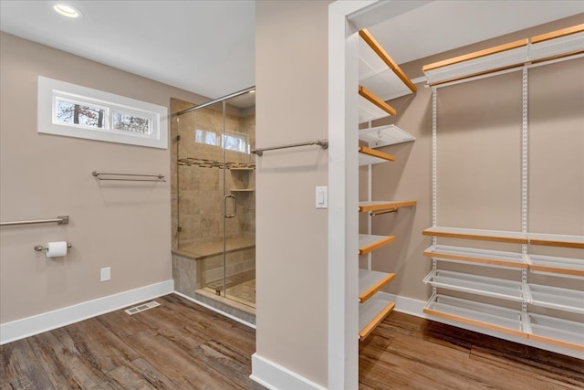 full bath with wood finished floors, baseboards, visible vents, recessed lighting, and a shower stall