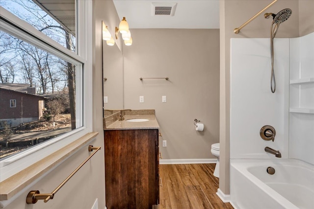 full bathroom with visible vents, toilet, wood finished floors, shower / bath combination, and vanity