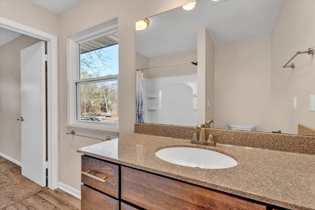 bathroom featuring vanity, a shower with shower curtain, wood finished floors, baseboards, and toilet