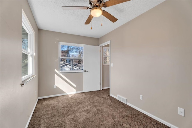 carpeted empty room featuring ceiling fan, baseboards, visible vents, and a textured ceiling