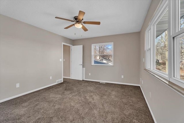 interior space with carpet, visible vents, baseboards, and ceiling fan