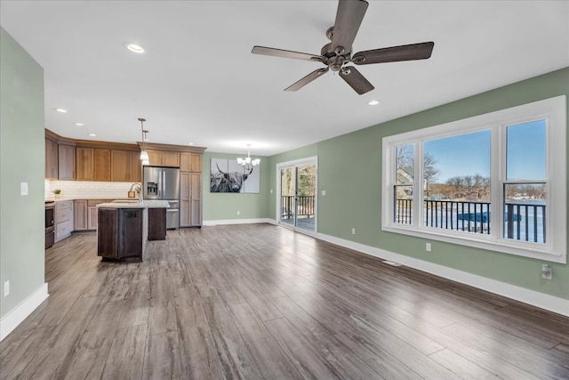 kitchen featuring light wood finished floors, light countertops, stainless steel fridge, open floor plan, and backsplash