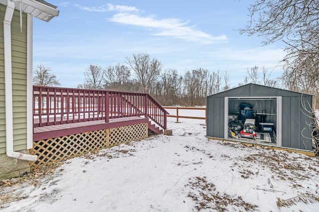 snowy yard featuring a storage unit and a deck