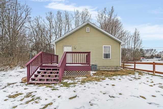 snow covered rear of property with a deck