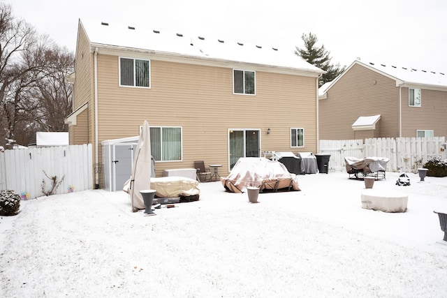 snow covered back of property with a storage unit