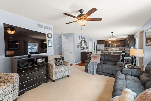 carpeted living room featuring ceiling fan with notable chandelier