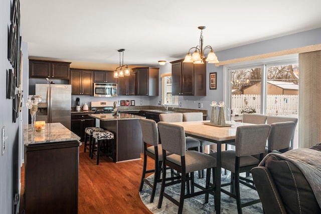 dining space with dark wood-type flooring, sink, and a chandelier