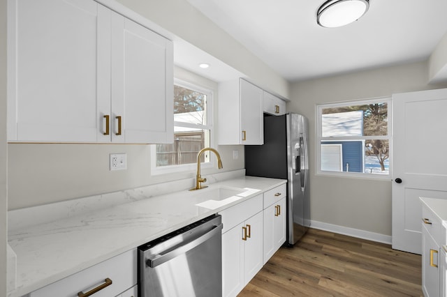 kitchen with light stone counters, white cabinetry, stainless steel appliances, and sink