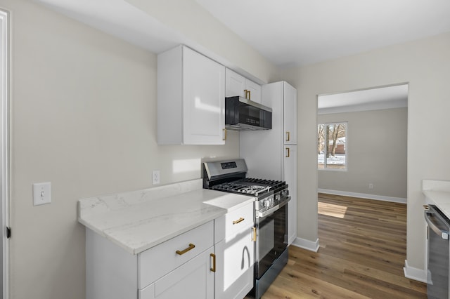 kitchen with appliances with stainless steel finishes, light stone countertops, light hardwood / wood-style floors, and white cabinets