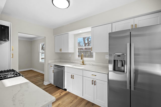 kitchen with plenty of natural light, appliances with stainless steel finishes, light stone countertops, and white cabinets