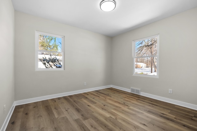 empty room featuring a healthy amount of sunlight and hardwood / wood-style floors