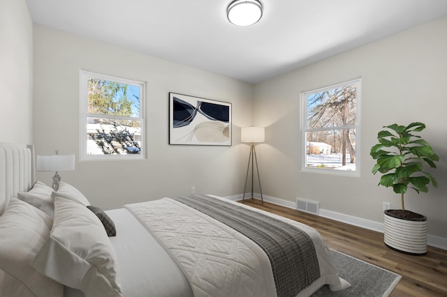 bedroom with multiple windows and dark hardwood / wood-style floors