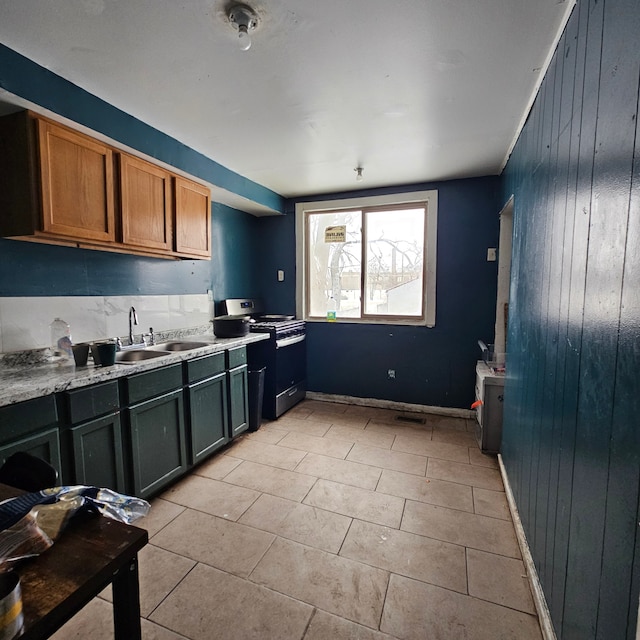 kitchen featuring sink, light tile patterned floors, and stainless steel gas stove