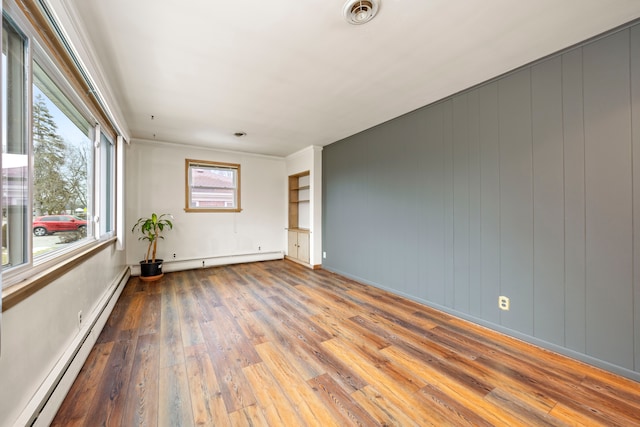 unfurnished room with baseboard heating and wood-type flooring