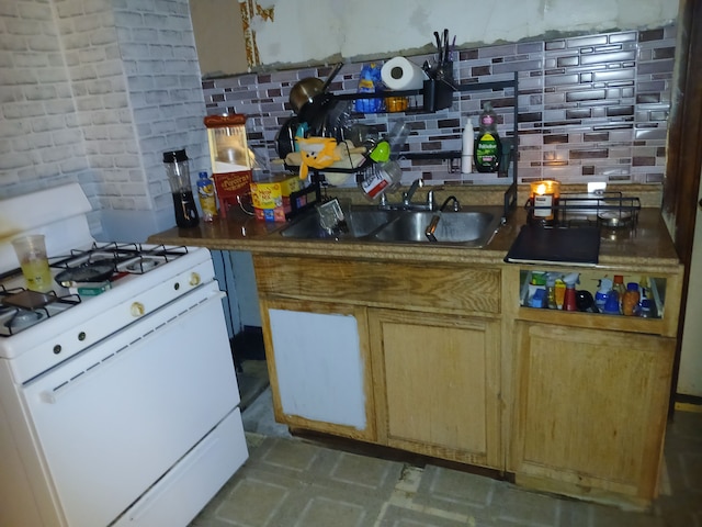 kitchen featuring white gas range, decorative backsplash, and a sink