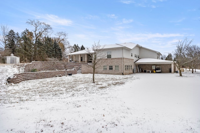 snow covered house featuring a storage unit