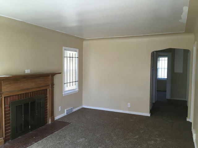 unfurnished living room featuring a fireplace and dark colored carpet