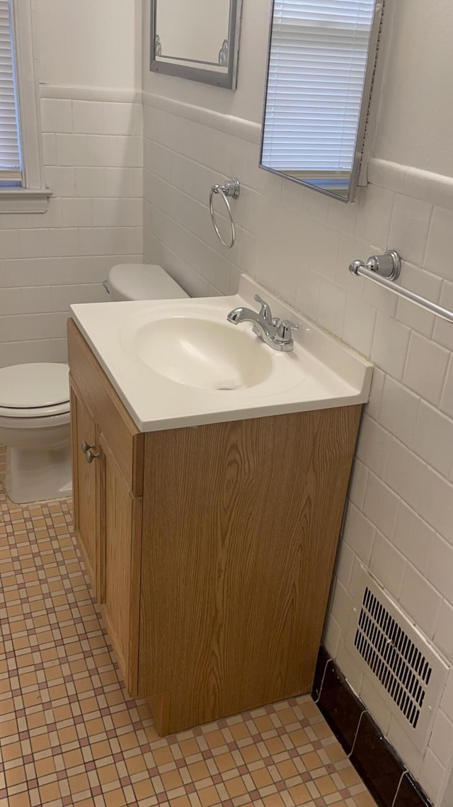 bathroom with vanity, tile walls, and toilet