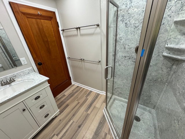 bathroom with an enclosed shower, vanity, and wood-type flooring