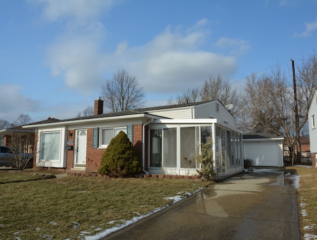 view of front of property with a garage, a sunroom, and a front lawn