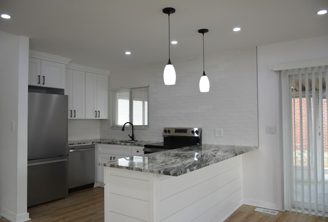 kitchen with sink, stone countertops, stainless steel appliances, kitchen peninsula, and white cabinets