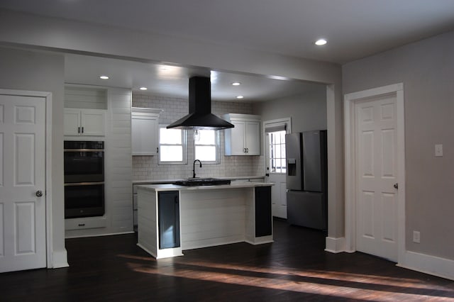 kitchen featuring a kitchen island, double oven, white cabinets, stainless steel fridge, and exhaust hood