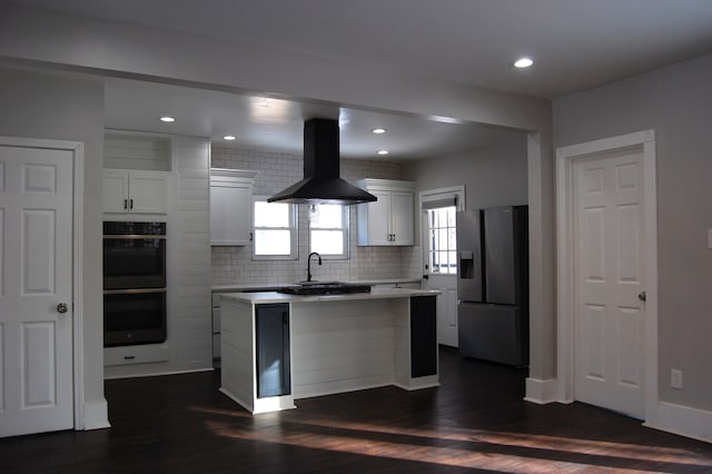 kitchen featuring stainless steel fridge, white cabinetry, range hood, black double oven, and a kitchen island