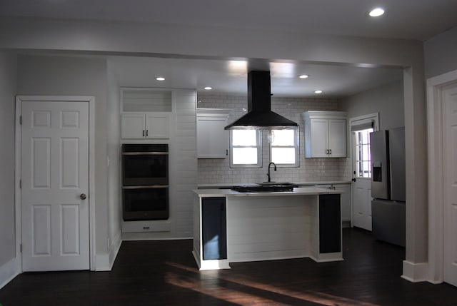 kitchen featuring a center island, ventilation hood, stainless steel fridge, double oven, and white cabinets