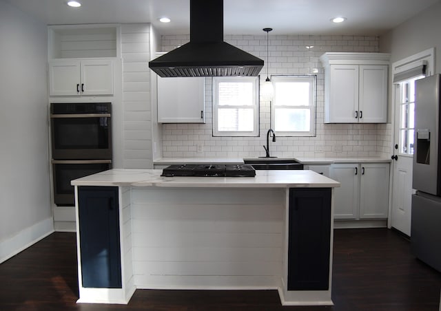 kitchen featuring appliances with stainless steel finishes, island range hood, tasteful backsplash, sink, and white cabinets