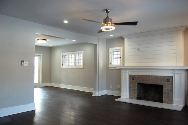 unfurnished living room with dark hardwood / wood-style flooring, ceiling fan, and a fireplace