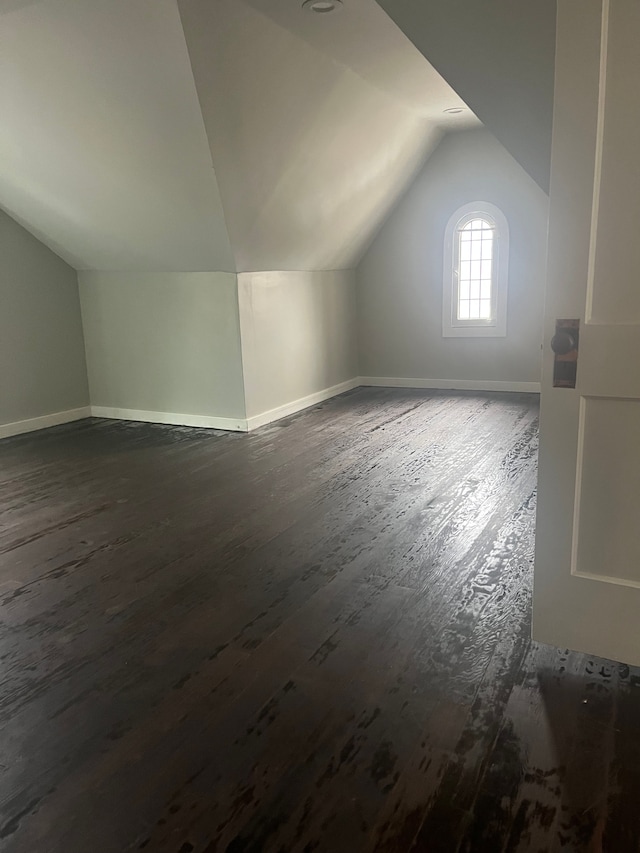 additional living space with vaulted ceiling and dark hardwood / wood-style floors