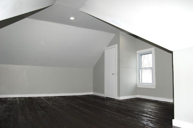 additional living space featuring lofted ceiling and dark hardwood / wood-style flooring