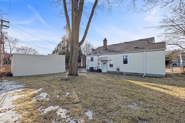 back of property with central AC and a lawn