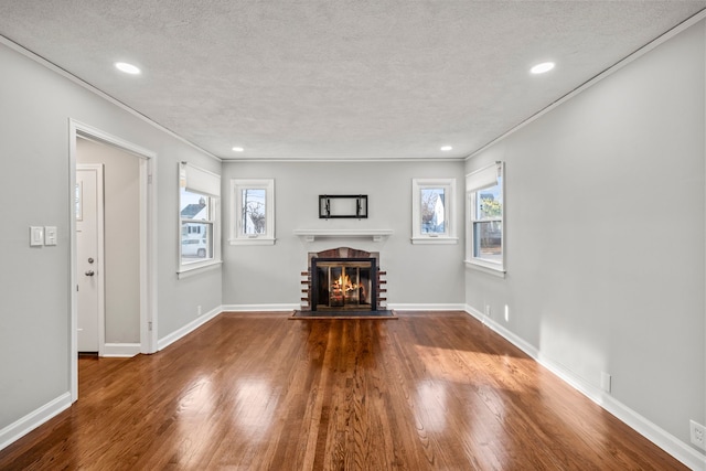 unfurnished living room with crown molding, a brick fireplace, dark wood-type flooring, and a textured ceiling