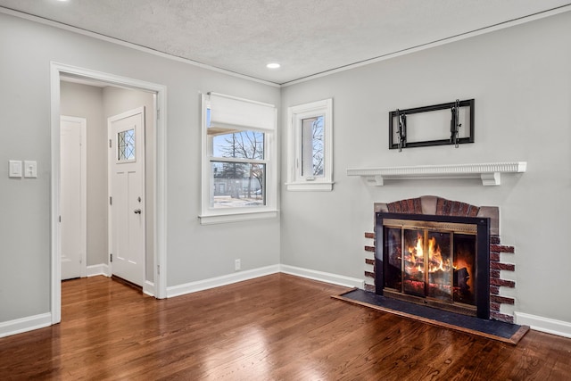 living room featuring dark wood-type flooring, crown molding, a brick fireplace, and a textured ceiling