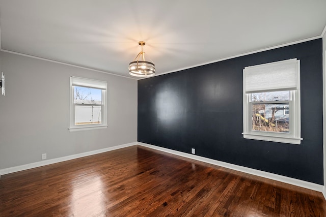 spare room featuring ornamental molding, dark hardwood / wood-style flooring, and a chandelier