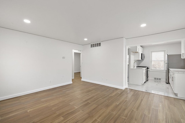 unfurnished living room with light wood-style floors, baseboards, visible vents, and recessed lighting