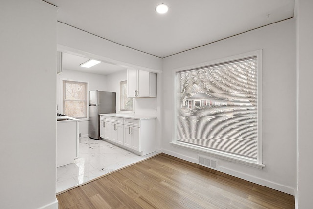 kitchen with visible vents, light countertops, freestanding refrigerator, and white cabinetry