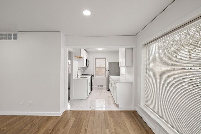 laundry room with light wood-type flooring, visible vents, and baseboards