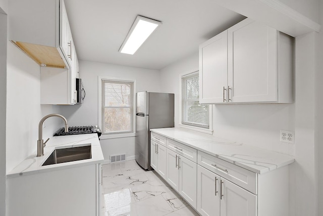 kitchen with marble finish floor, stainless steel appliances, visible vents, white cabinets, and a sink