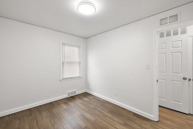 empty room with light wood-style floors, visible vents, and baseboards