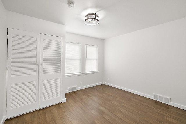 unfurnished bedroom featuring visible vents, baseboards, and wood finished floors