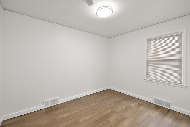 spare room featuring light wood-style floors, visible vents, and baseboards