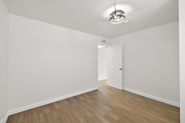 unfurnished room featuring baseboards, visible vents, and wood finished floors