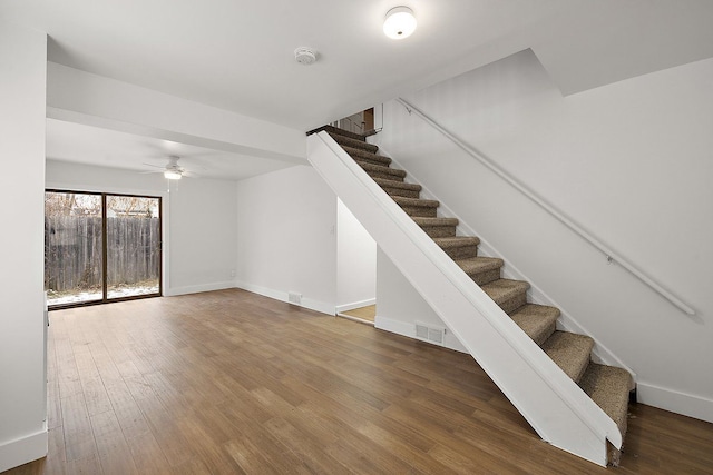 stairway with visible vents, baseboards, and wood finished floors