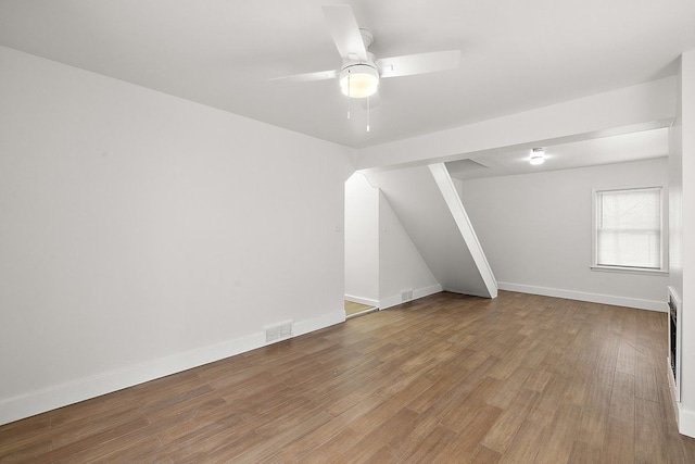 empty room featuring ceiling fan, wood finished floors, visible vents, and baseboards