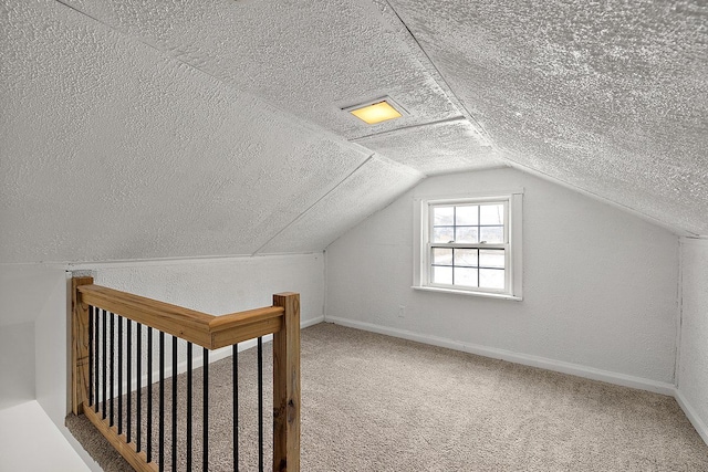 additional living space with vaulted ceiling, a textured ceiling, carpet, and baseboards