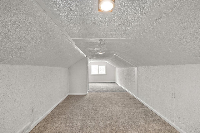 bonus room with a textured ceiling, baseboards, carpet flooring, and lofted ceiling