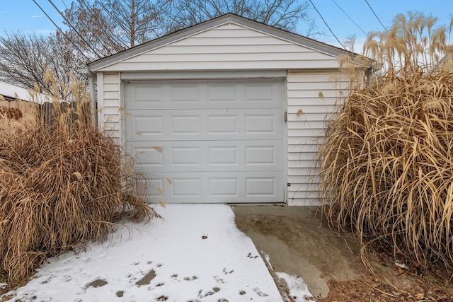 snow covered garage with fence